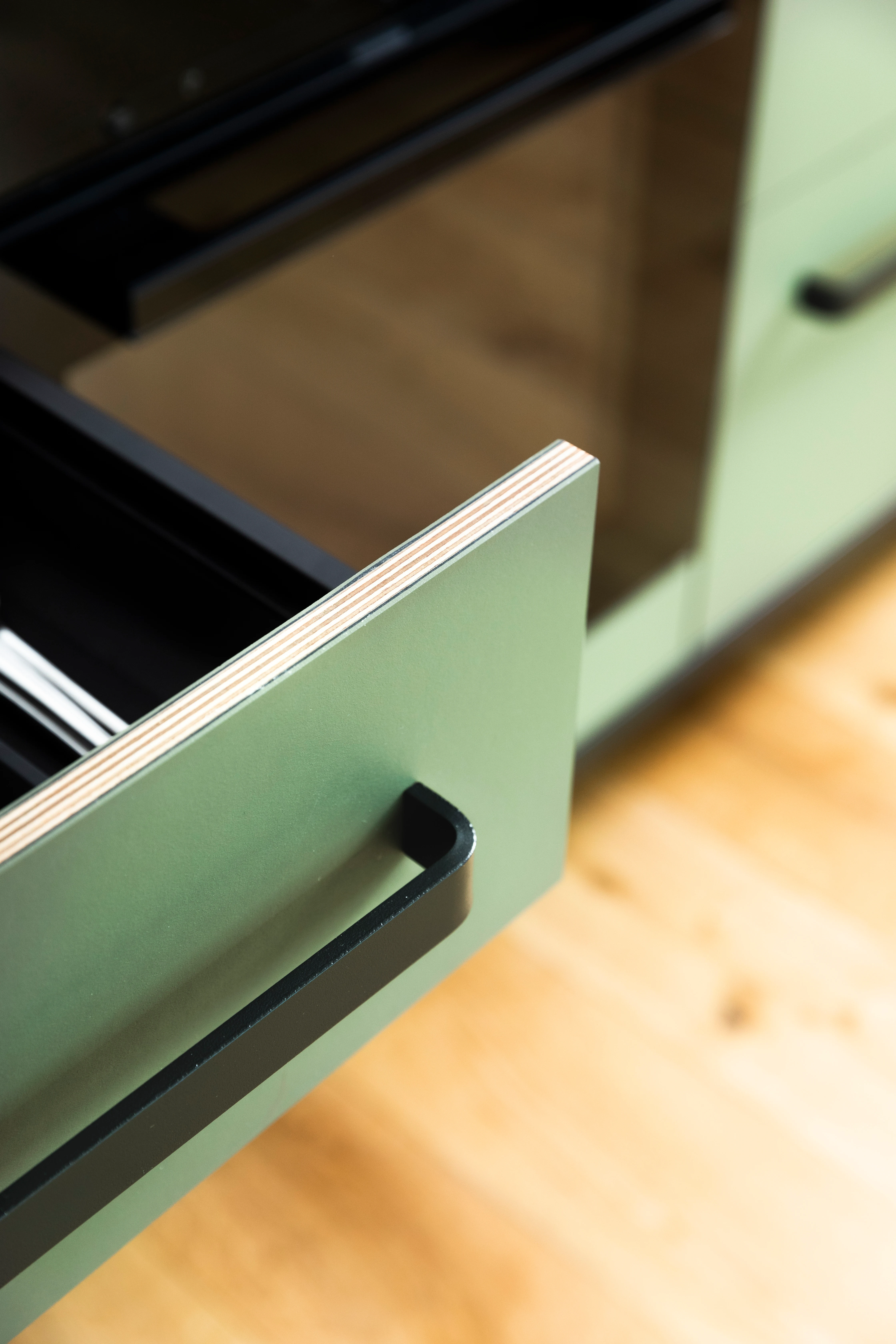 Detailaufnahme einer grünen Linoleum-Schublade in einer kitchen to keep, sichtbare Sperrholzkante zeigt den Materialaufbau