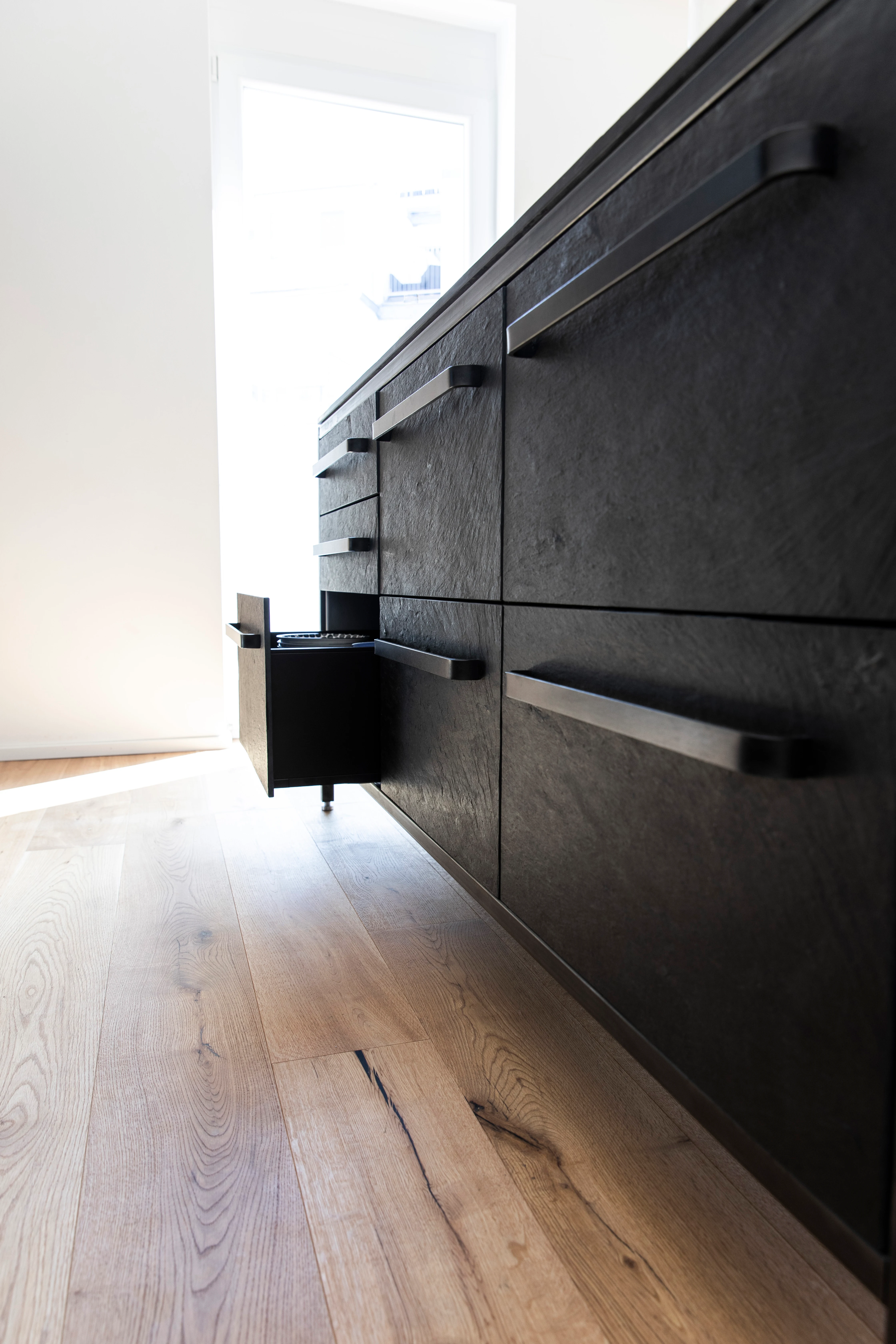 Schwarze Modulküche mit hellem Holzboden, minimalistisches keep Design im Wohnraum